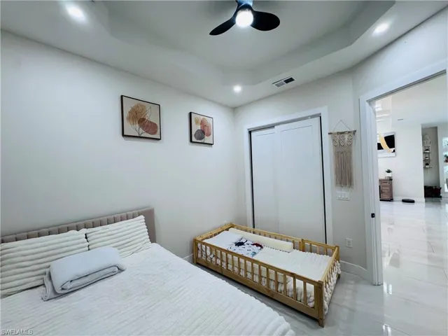 Bedroom with a closet, a raised ceiling, ceiling fan, and recessed lighting