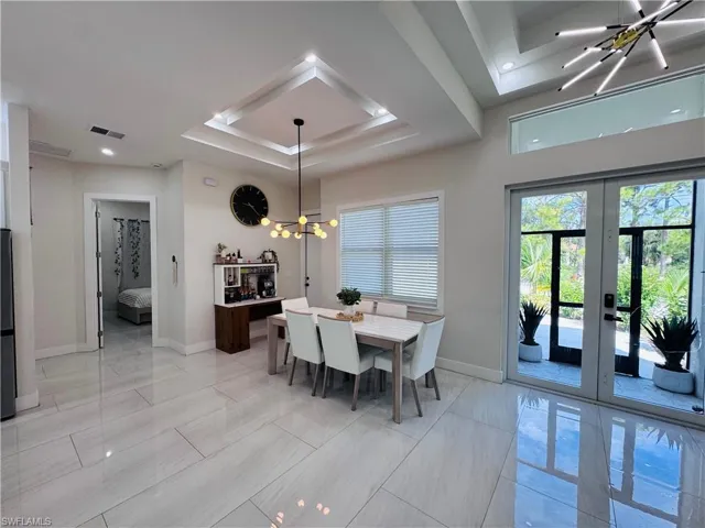 Dining area with a chandelier, a raised ceiling, and french doors