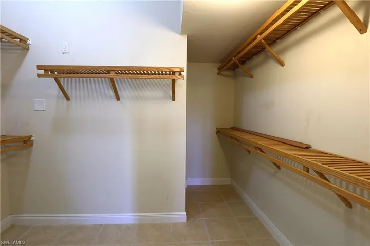 Storage area featuring wood-slat shelving and tile flooring