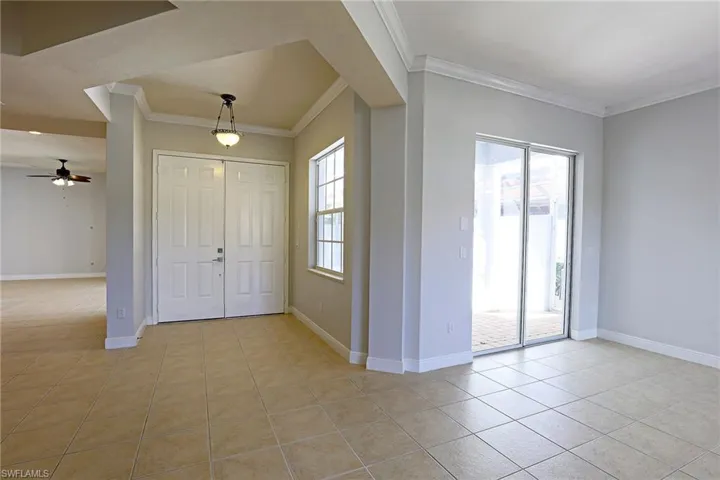Neutral-toned interior featuring ceramic tile flooring, double-door entry, sliding glass door, crown molding, and recessed lighting