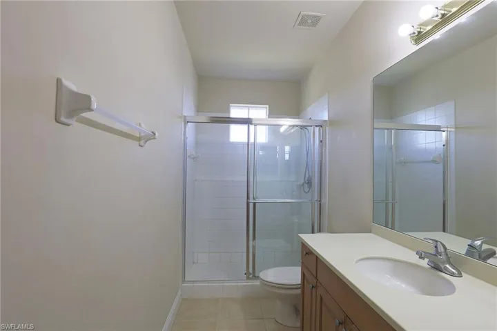 Bathroom vanity featuring a wood-finish cabinet, solid-surface countertop with integrated sink, and large wall-mounted mirror
