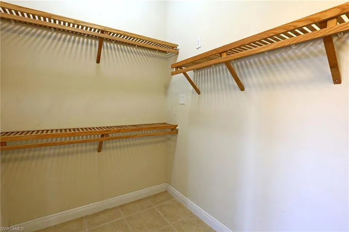 Primary Closet Storage space featuring multi-level wooden slatted shelving and tile flooring