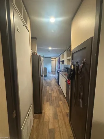 Kitchen featuring dark wood-style floors, freestanding refrigerator, black range oven, fridge, and white cabinets