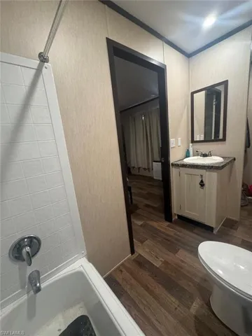 Bathroom with bathtub / shower combination, dark wood-style flooring, and vanity