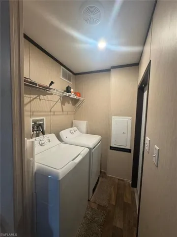 Laundry room featuring dark wood-type flooring, electric panel, and independent washer and dryer
