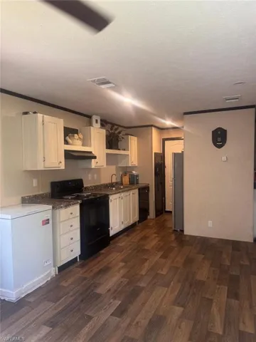 Kitchen with black appliances, open shelves, dark wood-type flooring, a textured ceiling, and white cabinetry