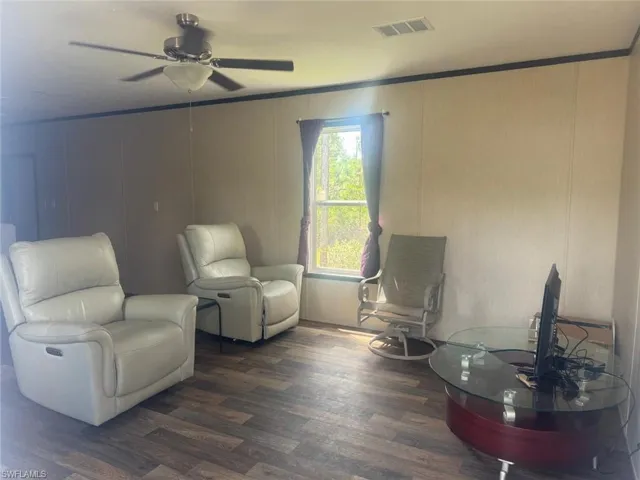 Sitting room featuring wood finished floors, crown molding, and a ceiling fan