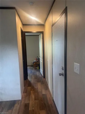 Hall with dark wood-style floors and crown molding