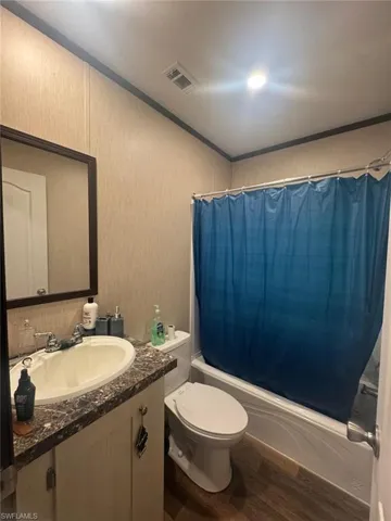 Bathroom featuring shower / bath combo, dark wood finished floors, vanity, and ornamental molding