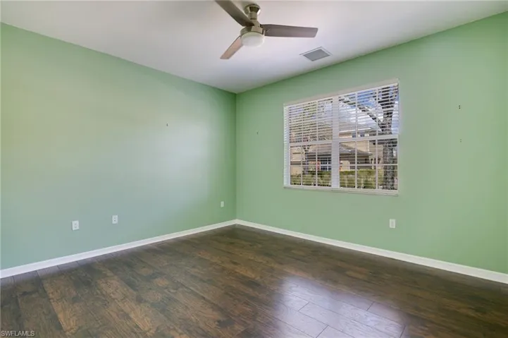 Empty room with dark wood-type flooring and a ceiling fan