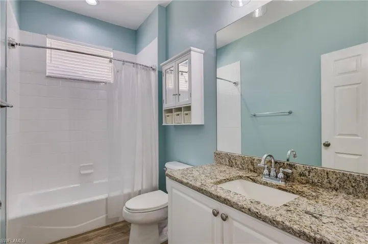 Full bath featuring vanity, shower / bath combo, and light wood-style flooring