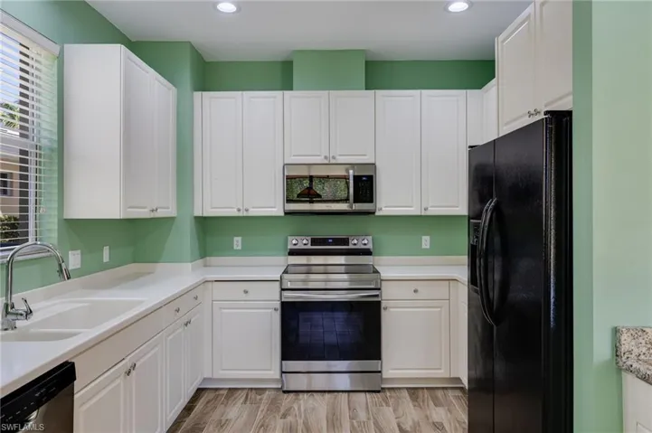 Kitchen with white cabinetry, stainless steel appliances, plenty of natural light, and light wood finished floors