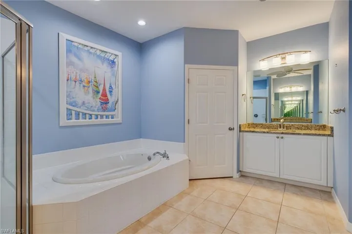 Full bathroom with vanity, a garden tub, light tile patterned floors, and a stall shower