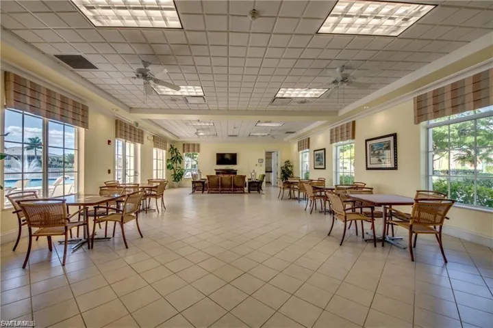 Dining area with ceiling fan, light tile patterned floors, and a paneled ceiling