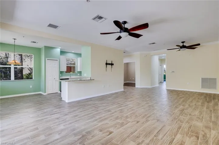 Unfurnished living room featuring wood finish floors, crown molding, and a ceiling fan