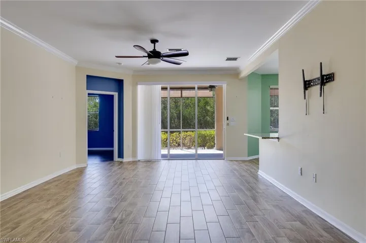 Empty room with wood finish floors, ceiling fan, and crown molding