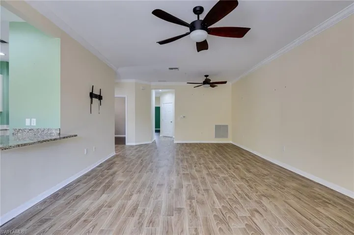 Unfurnished living room with wood tiled floors, ornamental molding, and a ceiling fan