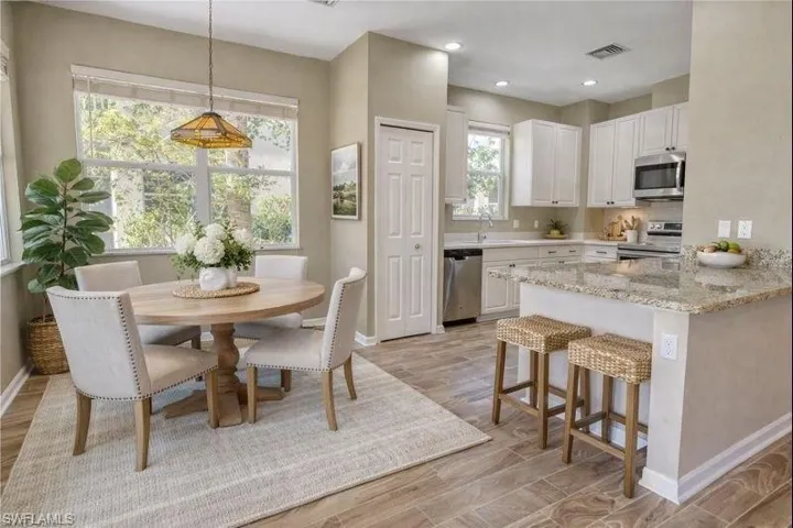 Virtually Staged Kitchen featuring light wood finished floors, white cabinets, stainless steel appliances, and light stone countertops