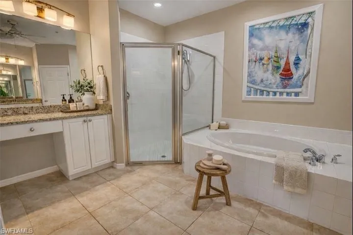 Virtually staged Bathroom with a bath, vanity, a stall shower, ceiling fan, and light tile patterned flooring
