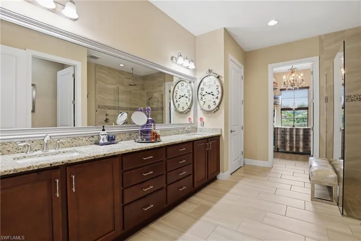 Full bath with double vanity, a shower stall, hanging lights, and wood tiled floors