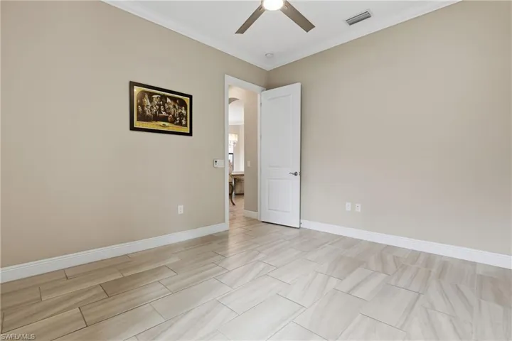 Unfurnished room with arched walkways, crown molding, and a ceiling fan
