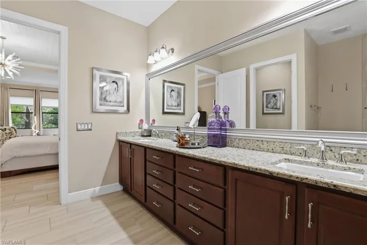 Bathroom with double vanity, ensuite bathroom, wood finish floors, and ornamental molding