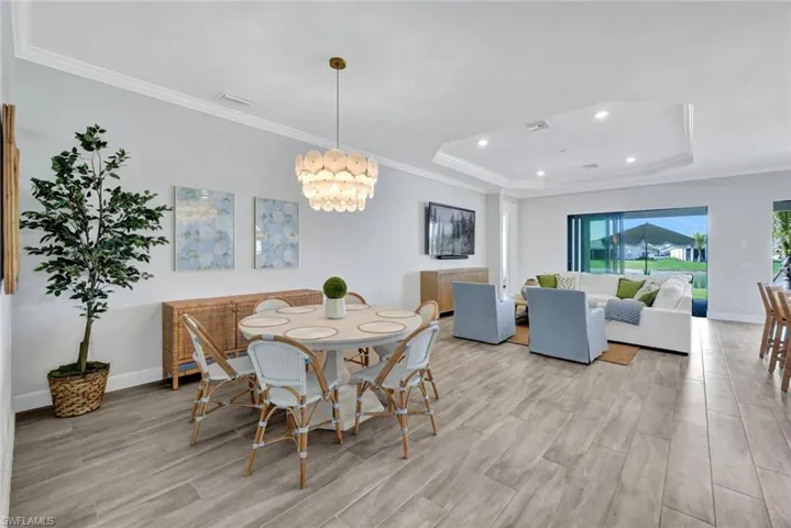 Dining space with visible vents, crown molding, light wood finished floors, baseboards, and a raised ceiling