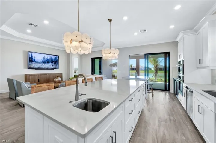 Kitchen with visible vents, crown molding, recessed lighting, a center island with sink, and a sink