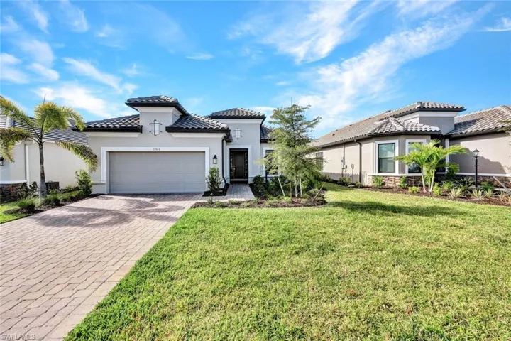 Mediterranean / spanish-style home with a front yard, stucco siding, an attached garage, a tiled roof, and decorative driveway