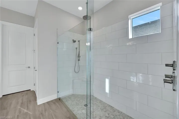Bathroom featuring wood finished floors, baseboards, and walk in shower