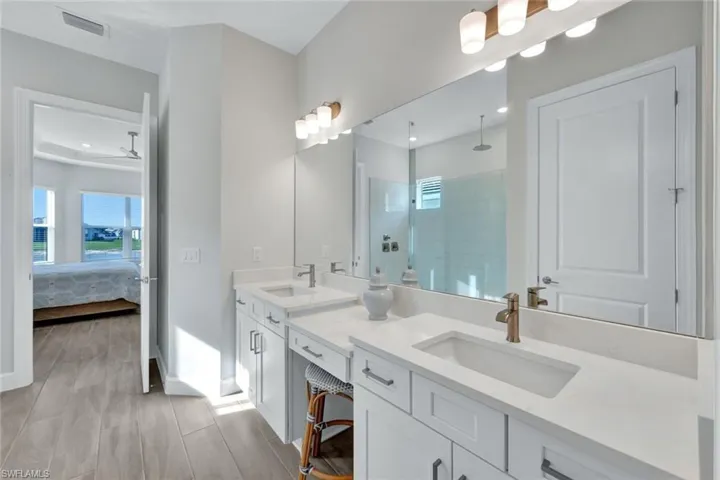 Full bathroom featuring double vanity, a sink, tiled shower, and visible vents