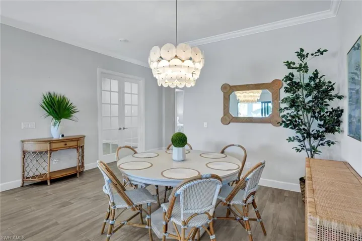 Dining room with baseboards, ornamental molding, wood finished floors, and french doors