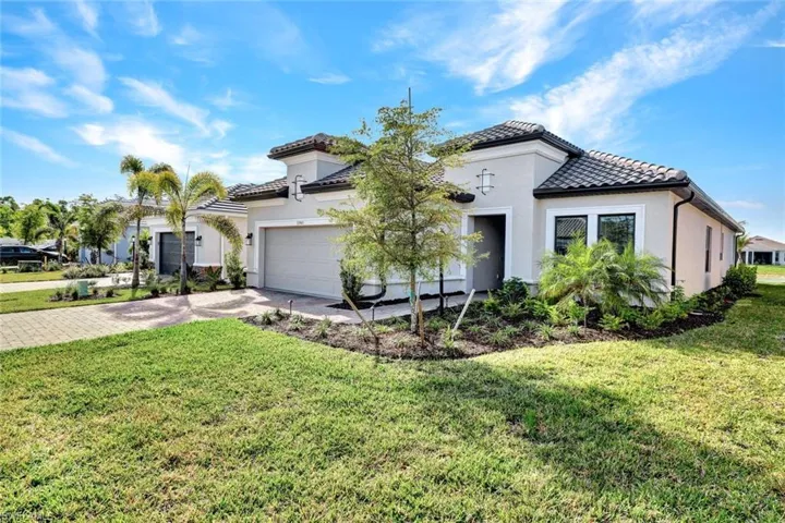 Mediterranean / spanish-style home with a front lawn, driveway, stucco siding, and a tile roof