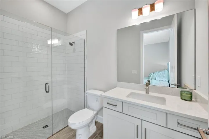 Bathroom with connected bathroom, toilet, wood finished floors, and a shower stall