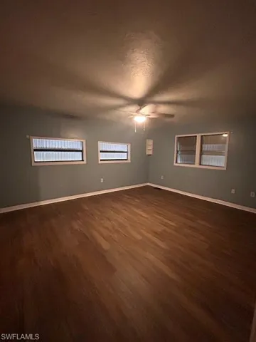 Spare room featuring a textured ceiling, dark wood-type flooring, and ceiling fan