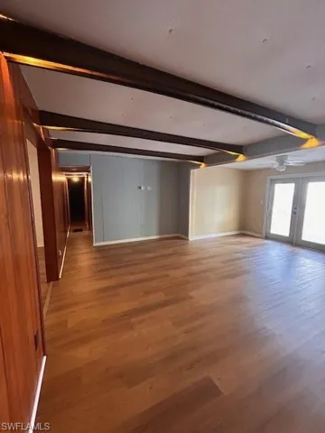 Spare room featuring french doors, beamed ceiling, and hardwood / wood-style floors