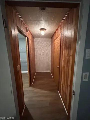 Corridor with dark hardwood / wood-style floors and wooden walls