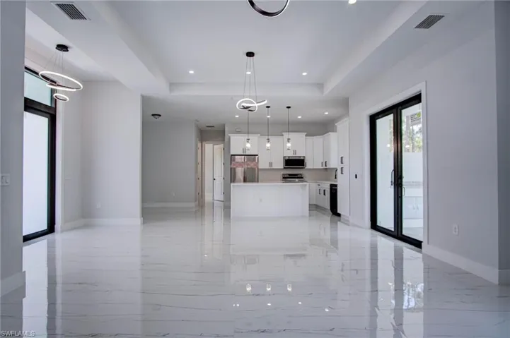 Kitchen featuring hanging light fixtures, appliances with stainless steel finishes, light tile patterned flooring, and a tray ceiling