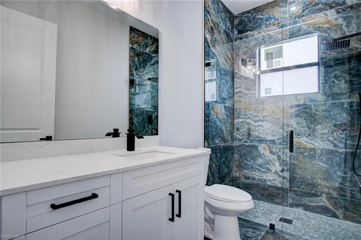 Bathroom featuring vanity, an enclosed shower, and toilet