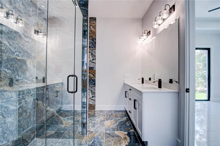 Bathroom featuring tile patterned floors, double sink vanity, and an enclosed shower