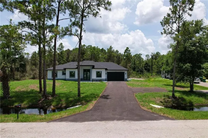 Ranch-style home featuring a garage and a front lawn