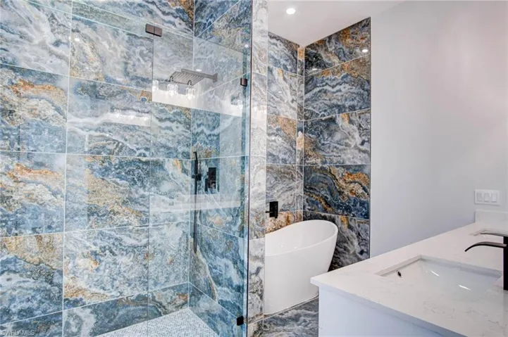 Bathroom featuring vanity, separate shower and tub, and tile walls