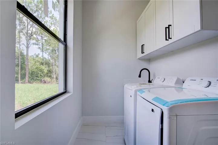 Clothes washing area featuring light tile patterned floors, separate washer and dryer, and cabinets
