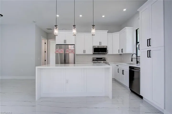 Kitchen with a center island, decorative backsplash, stainless steel appliances, and decorative light fixtures