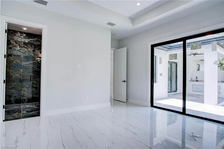 Unfurnished room with ceiling fan, light tile patterned floors, and a tray ceiling