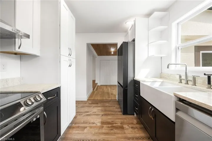 Kitchen featuring white cabinetry, light hardwood / wood-style flooring, stainless steel appliances, and range hood