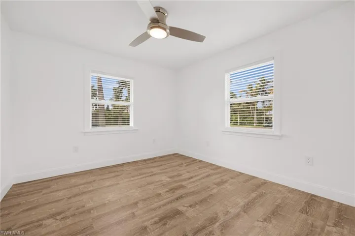 Spare room featuring light wood-type flooring, ceiling fan, and a healthy amount of sunlight
