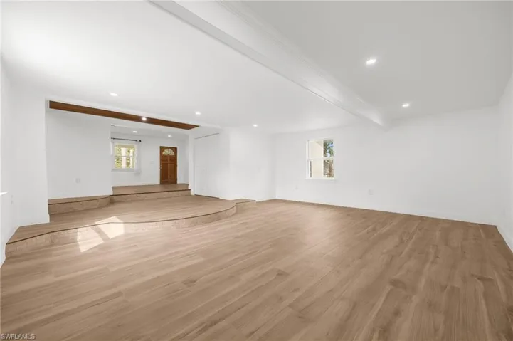 Unfurnished living room with beamed ceiling and light hardwood / wood-style floors
