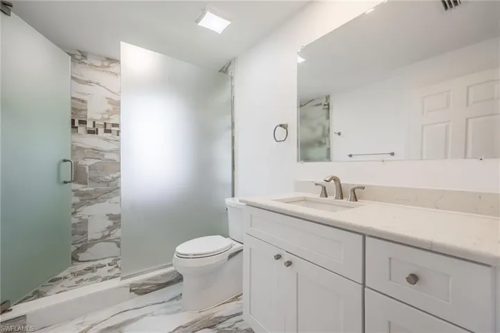 Bathroom featuring vanity, toilet, and a shower with door