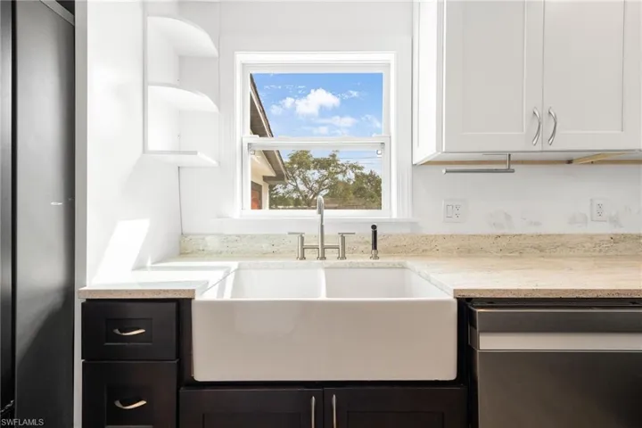 Kitchen with deep sink, light stone countertops, sink, and white cabinetry